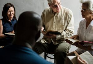 Several people studying Scripture together with different Bible translations open on a table.